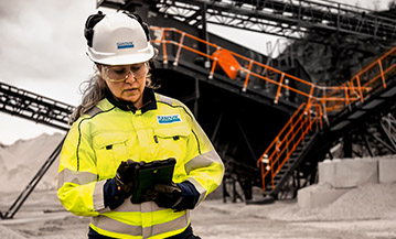 Woman in work clothes and helmet in front of a crushing and sorting plant (photo)