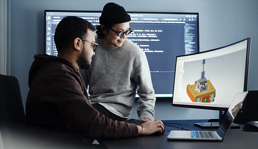 Two man looking at a screen displaying a CAD model of a component. (photo)