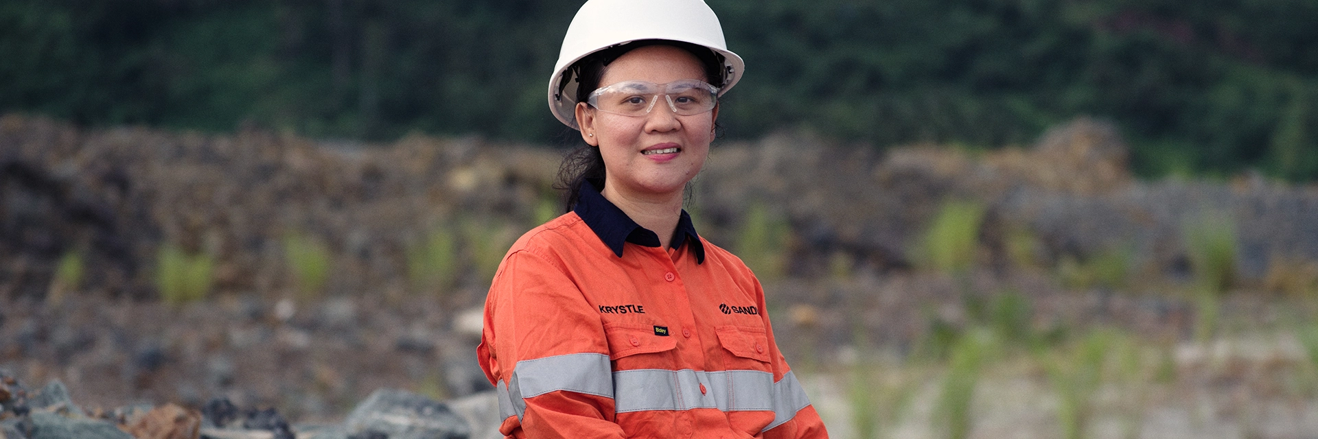 Woman with helmet and protective gear sitting on a rock (photo)
