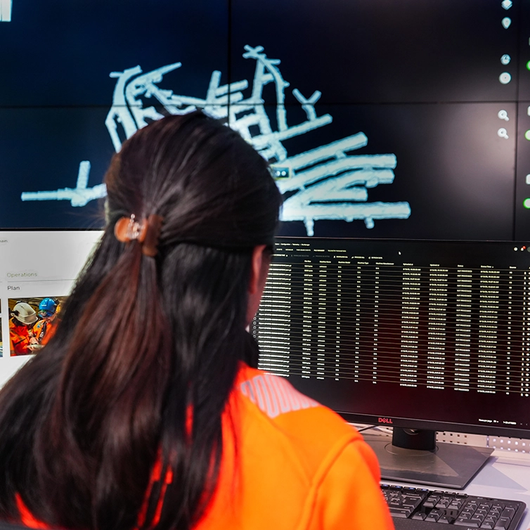 Woman sitting in front of screens in a control room (photo)