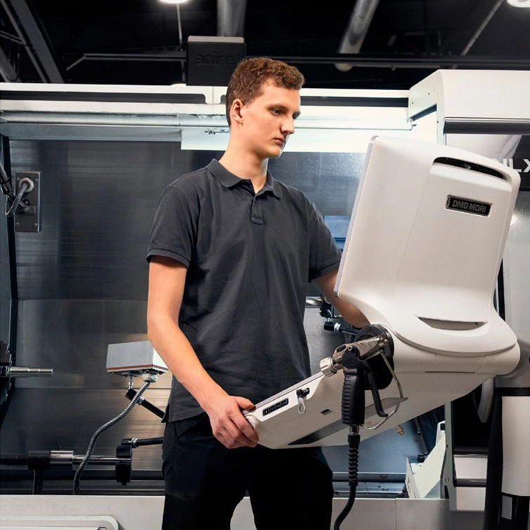 Man vid skärm intill CNC-maskin (foto)